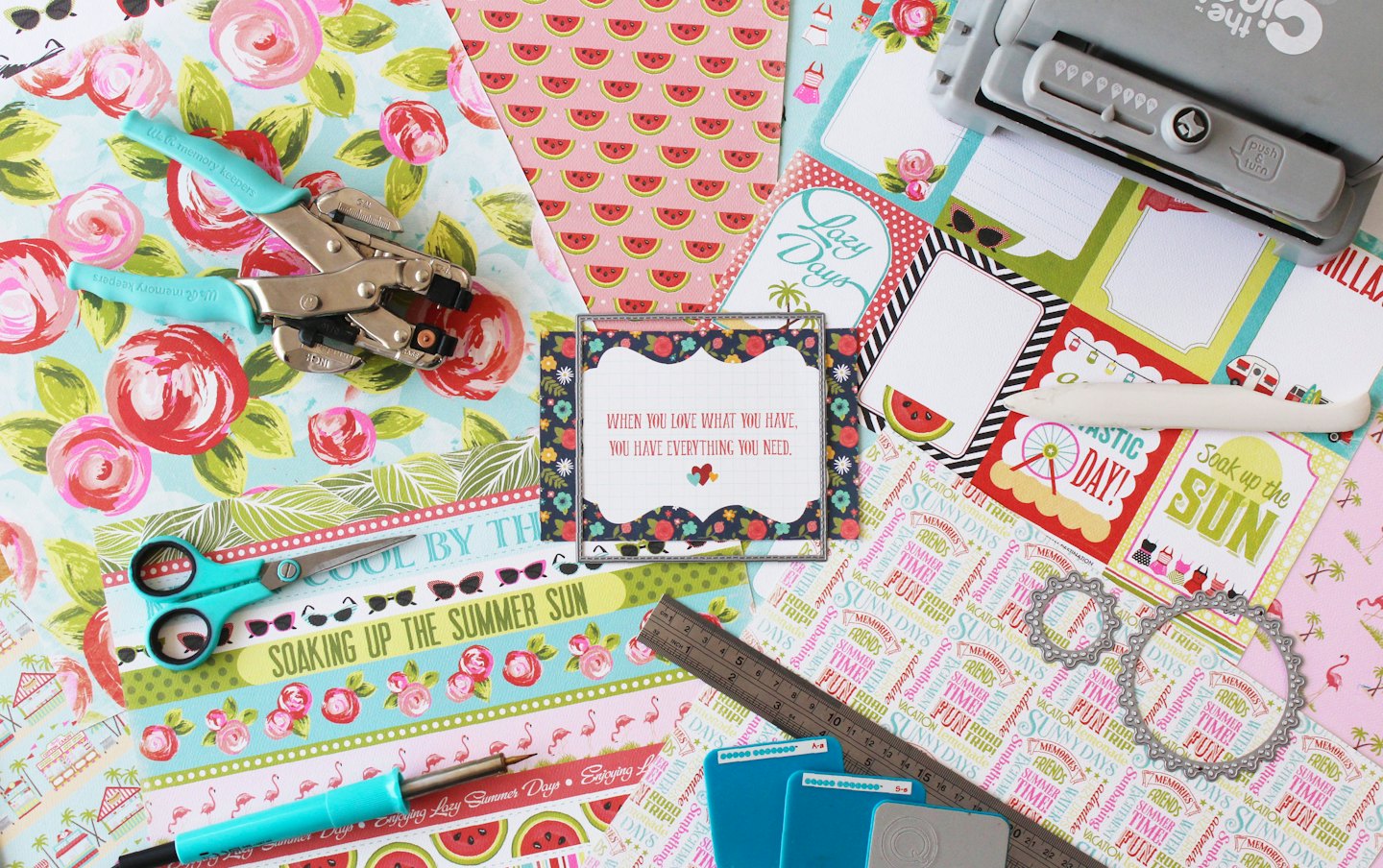 Overhead view of colorful scrapbooking paper and crafting tools.