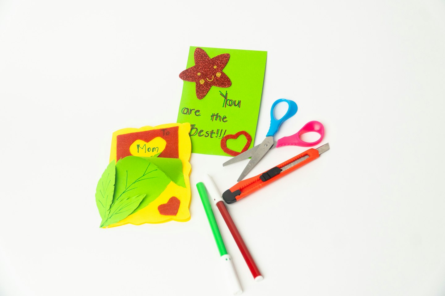 Handmade greeting cards and craft supplies arranged on white surface.